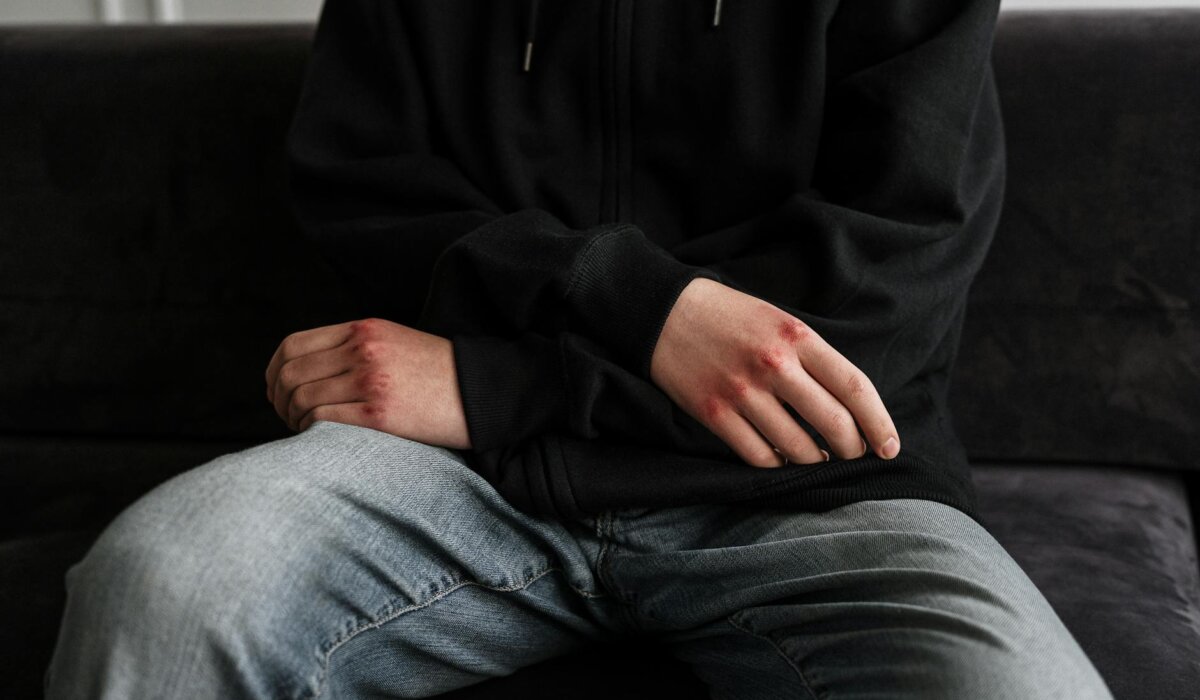 person in black jacket and blue denim jeans sitting on black couch