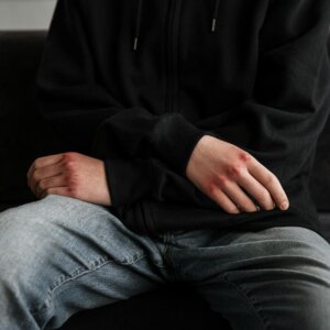 person in black jacket and blue denim jeans sitting on black couch