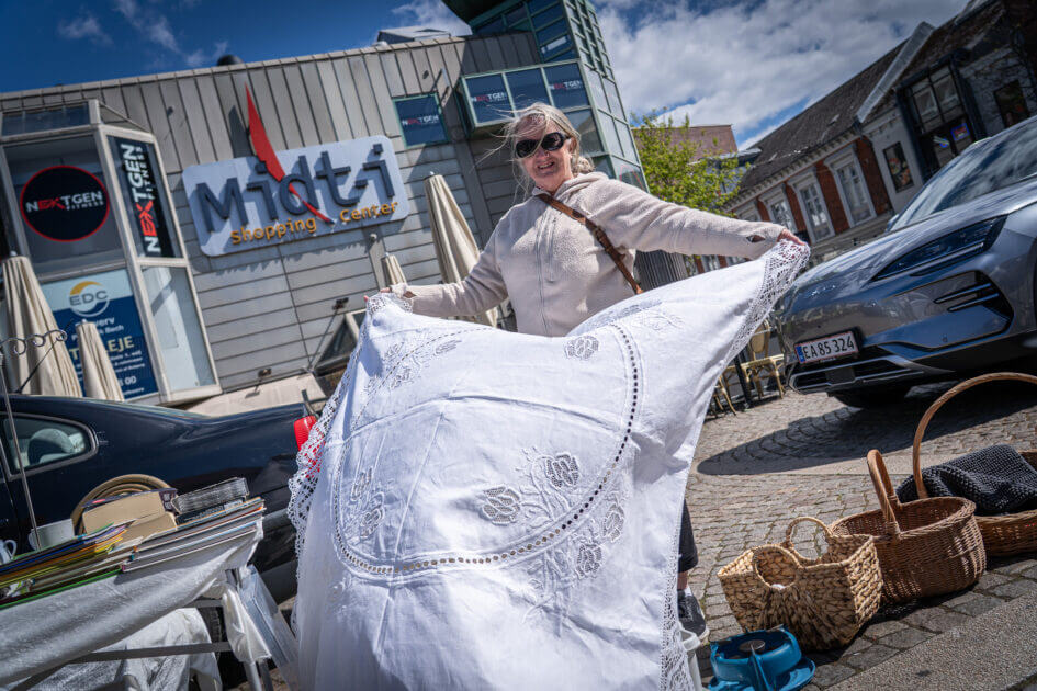 Formand for Esbjerg Kræmmerforening, Ellen Margrethe Gregersen, viser en fin, hvid dug frem ved sin bod på Torvet. Hun har stået i spidsen for foreningen i fem år. Foto: Fjodor Pedersen.