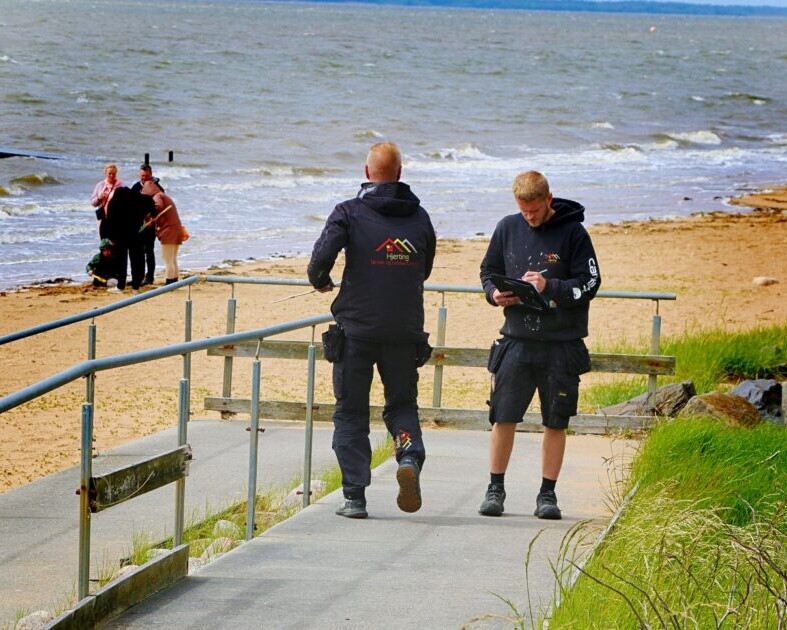 Arbejdet dokumenteres, mens strandgæster nyder udsigten og vinden ved vandet. Foto: Johnny Tauman.