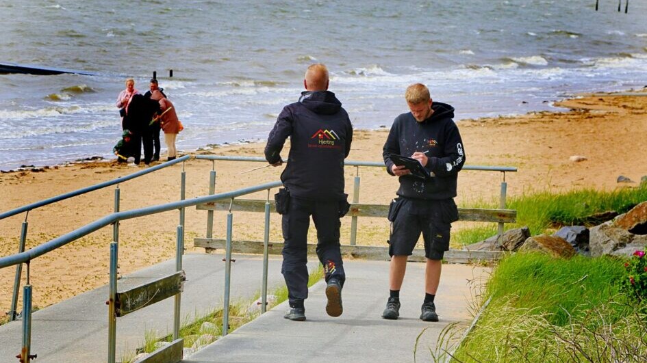 Arbejdet dokumenteres, mens strandgæster nyder udsigten og vinden ved vandet. Foto: Johnny Tauman.