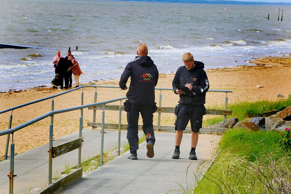 Arbejdet dokumenteres, mens strandgæster nyder udsigten og vinden ved vandet. Foto: Johnny Tauman.