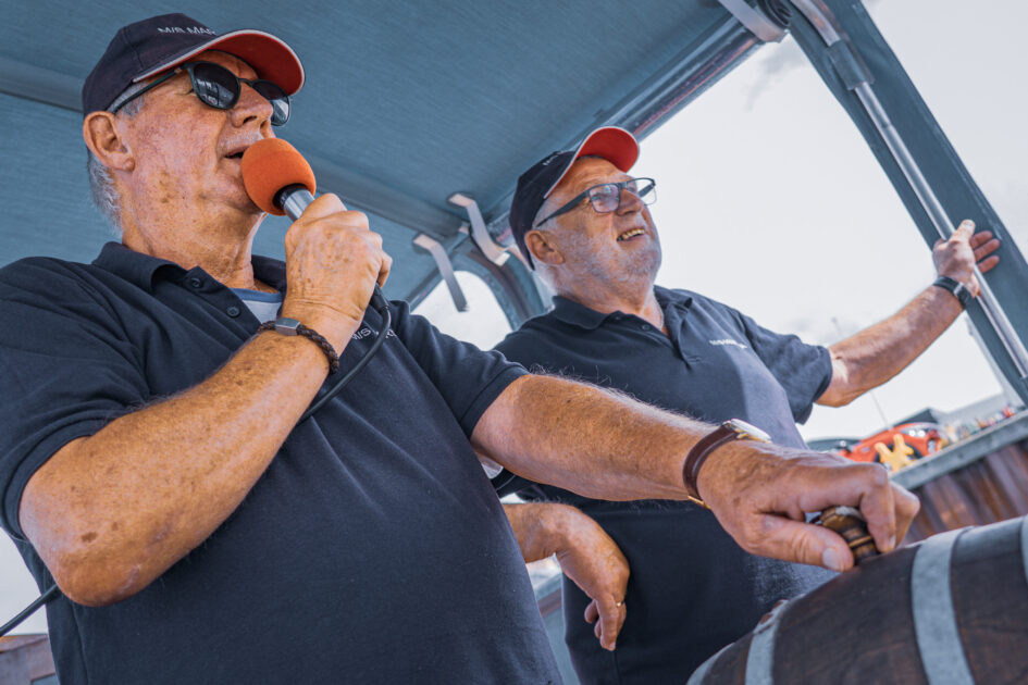 Skipper Torben Korsgaard og hans gast Poul Knudsen styrer båden sikkert ud af havnen – med både mikrofon og glimt i øjet. Foto: Fjodor Pedersen.