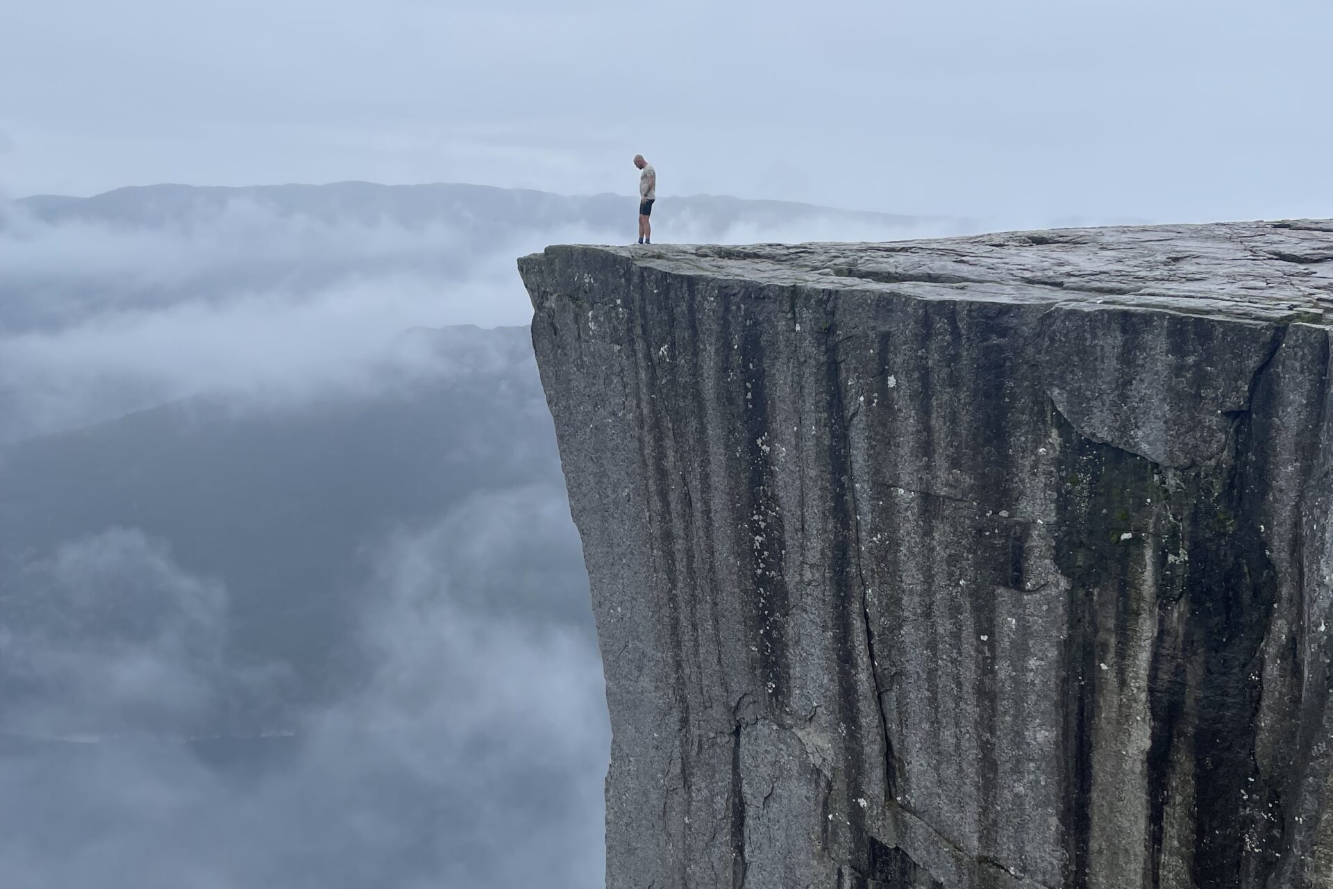 På kanten af verden: En bjergbestiger står på Preikestolen og kigger ud over tågerne. Privatfoto.