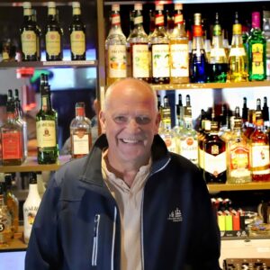 Med smil og livsglæde tager Viknar imod gæsterne – bag ham vidner flasker og spiritus om mange hyggelige aftener på Bibas. Foto: Johnny Tauman.