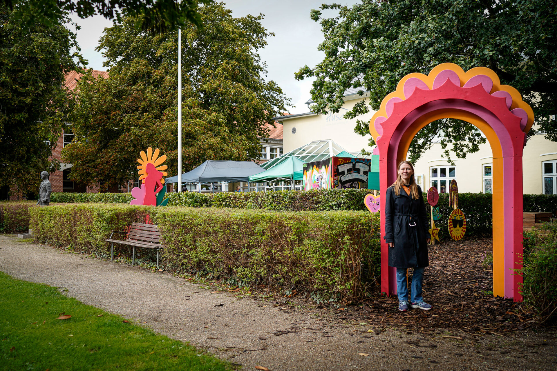 Pigerne har arbejdet på at skabe et nyt samlingssted med bænke, blomster og farverige skilte. Området skal fungere som et frirum for unge, der savner et sted at mødes, som er deres eget – væk fra de mere traditionelle, kommercielle tilbud i bymidten. Her er det kulturfacilitator Mia Skovgaard, der agerer model ved indgangsportalen. Foto: Fjodor Pedersen.