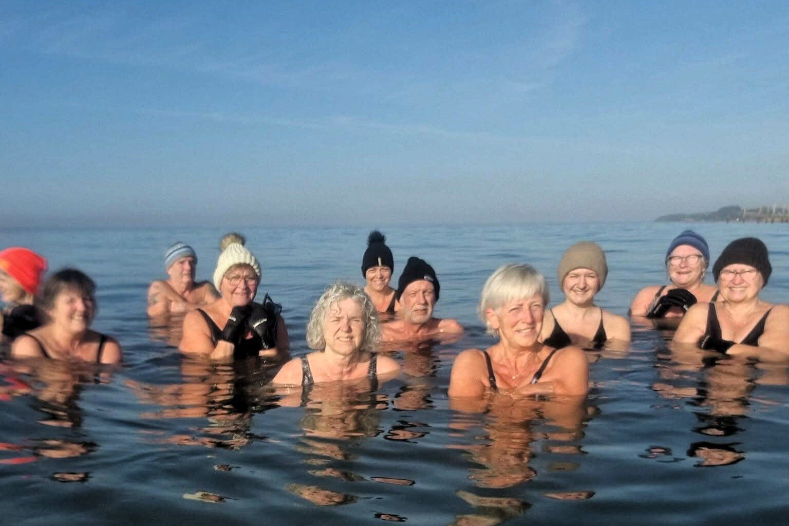 Hue på hovedet og smil på læben – vinterbadning giver både varme og energi. Privatfoto.