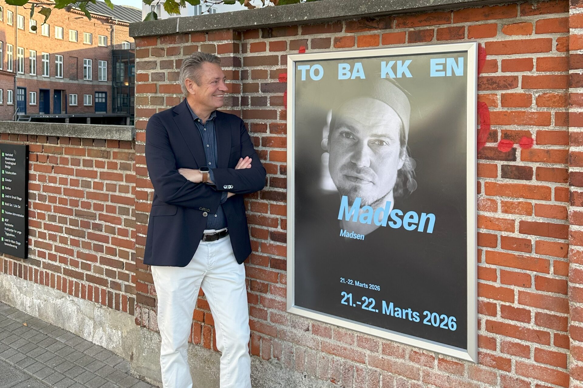 Torben Seldrup, direktør for Musikhuset og Tobakken, ved siden af et eksempel på den nye identitet i Tobakkens visuelle kommunikation. Pressefoto.