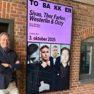 Torben Seldrup, direktør for Musikhuset og Tobakken, ved siden af et eksempel på den nye identitet i Tobakkens visuelle kommunikation. Pressefoto.