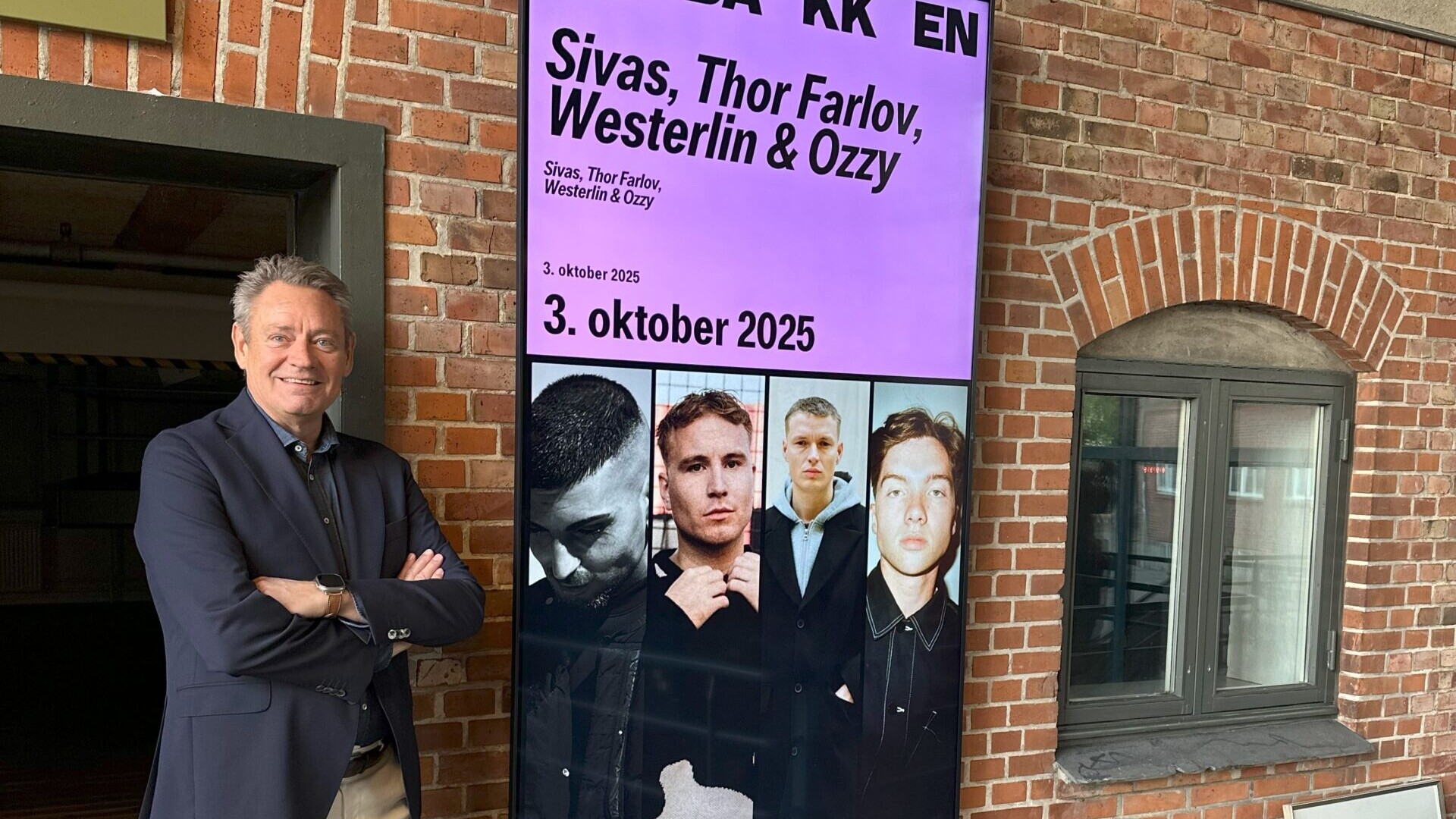 Torben Seldrup, direktør for Musikhuset og Tobakken, ved siden af et eksempel på den nye identitet i Tobakkens visuelle kommunikation. Pressefoto.