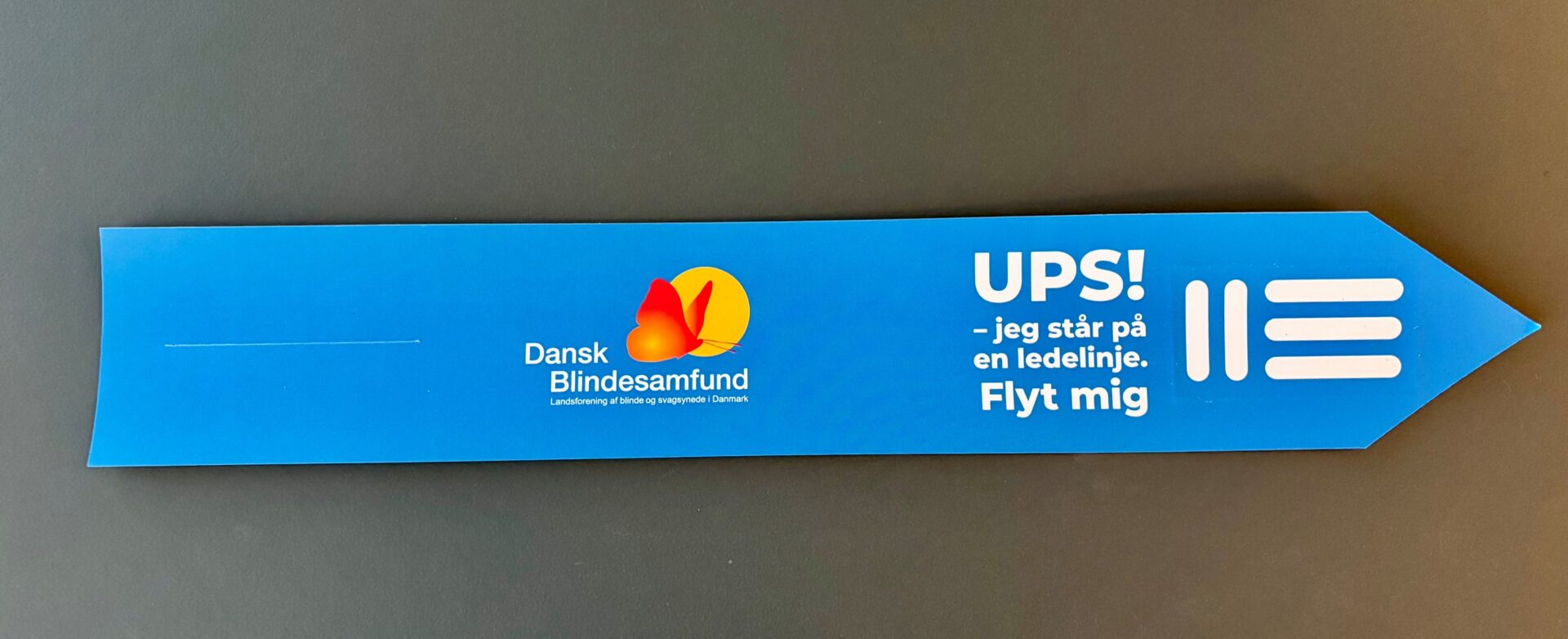 De blå bagagetags med teksten "Ups! Jeg står på en ledelinje. Flyt mig" bliver brugt i hele landet for at skabe opmærksomhed på at holde ledelinjer fri til blinde og svagsynede