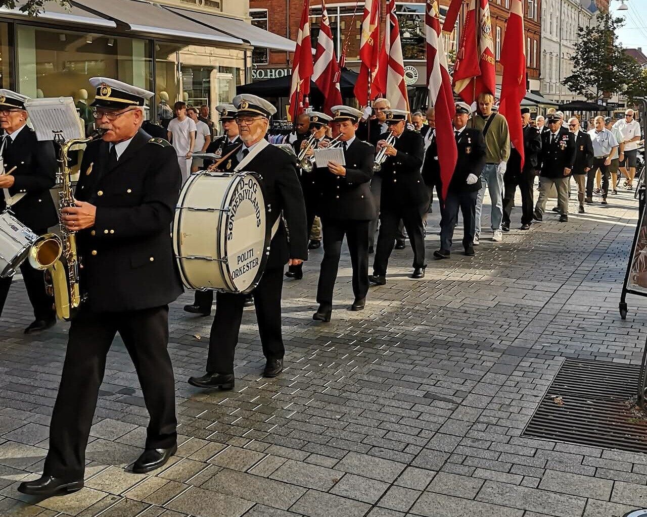 Syd- og Sønderjyllands Politiorkester på marchtur en sommerdag i gågaden. Privatfoto.