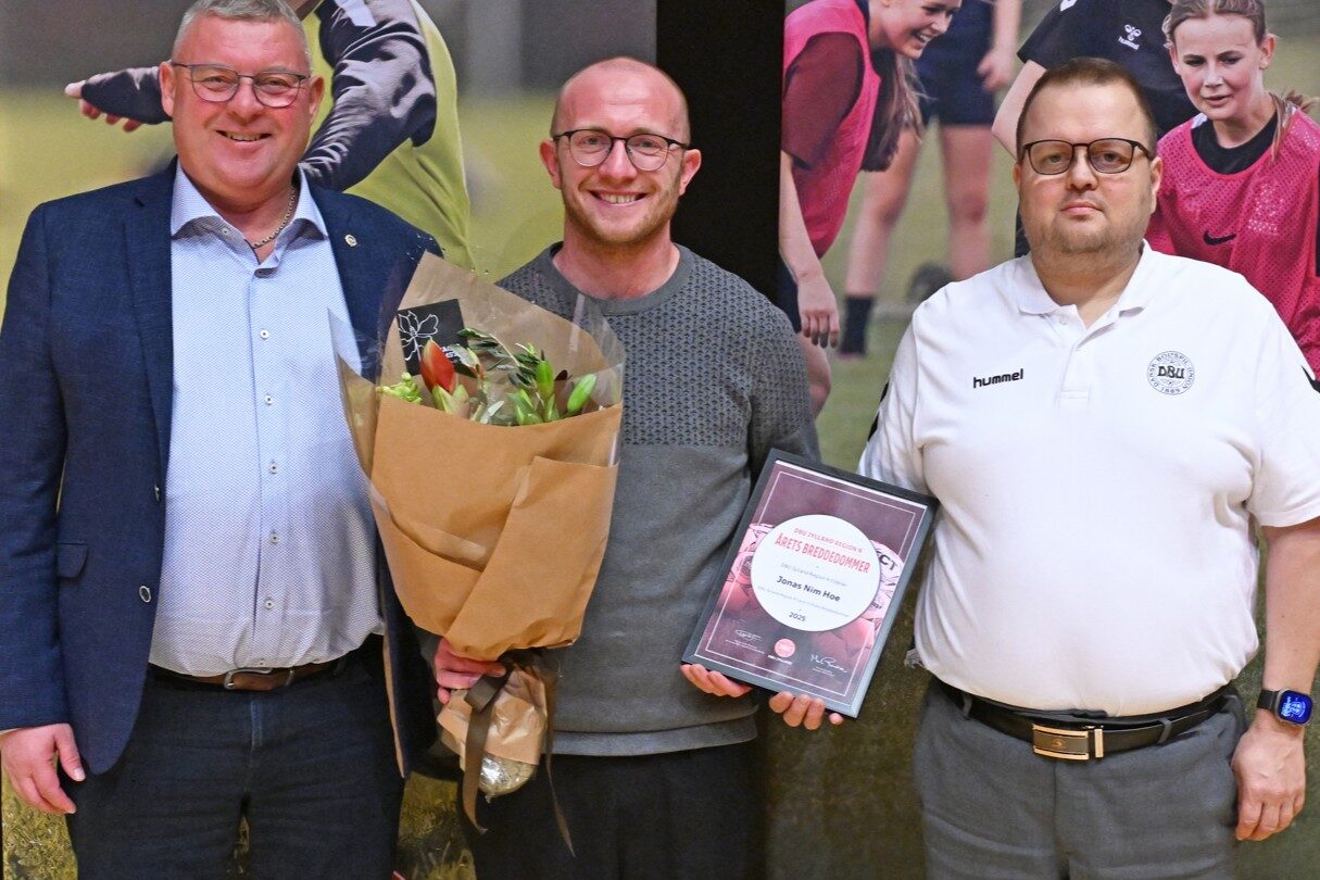 Jonas Nim Hoé (i midten) modtager prisen som Årets Breddedommer 2025 i DBU Jylland Region 4. Han blev hædret af Dennis Christiansen fra DBU Jylland Dommerregion 4 (th.) og regionsbestyrelsesmedlem John Møller Pedersen (tv.). Foto: LLN Press.