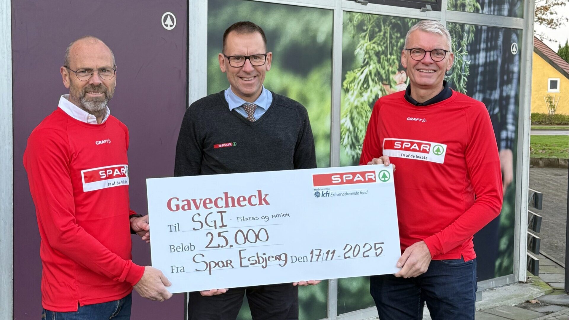 SPAR-købmand Hans Boel Lauridsen overrækker en gavecheck på 25.000 kroner til SGI Fitness & Motion foran butikken i Østerbyen.