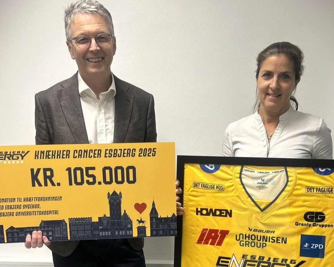 På billedet ses Frede Donskov, professor og overlæge i kræftsygdomme, og Lone Gamrath, ph.d.-studerende i kræftforskning, som modtager checken på 105.000 kroner og den signerede Knæk Cancer-trøje fra Esbjerg Energy.
