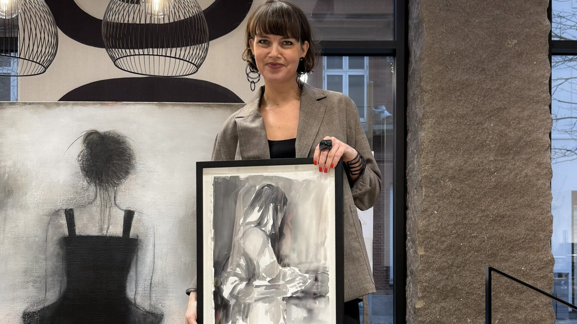 Marie Lahn Adamsen med to af værkerne fra den kommende kunstsalon. Det store billede er af Susy Grundahl, mens det mindre værk er skabt af Siri Gindesgaard. Privatfoto.