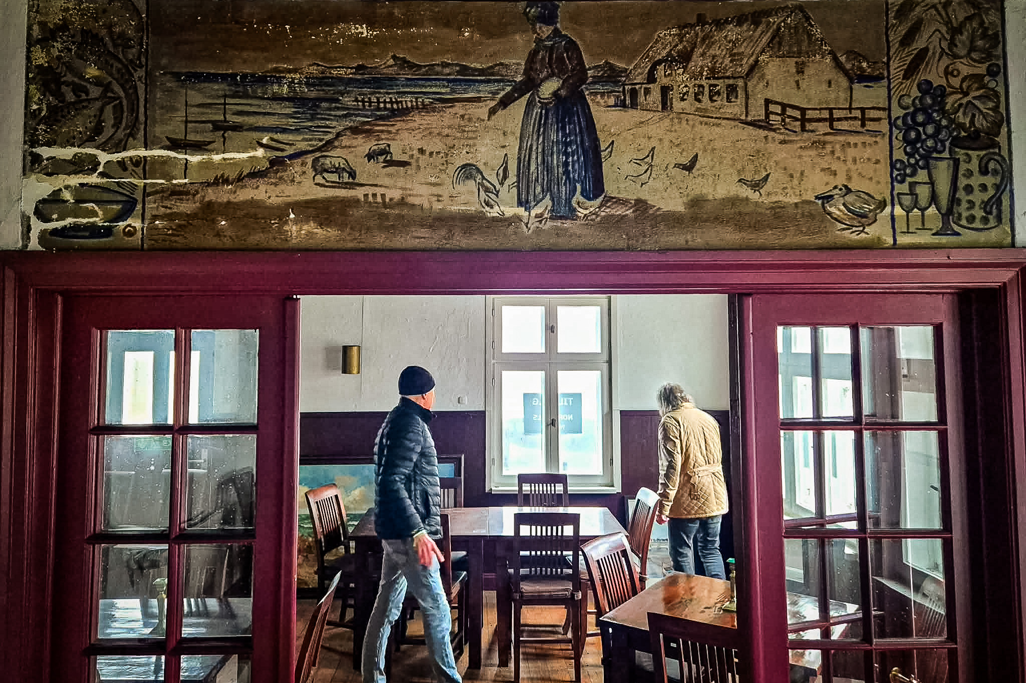 Frisen over døren på Sønderho Badehotel er udført af kunstneren Franz Reinhold List (1898-1986). Motivet med Fanøkvinde i folkedragt, klitlandskab, hav og lokale symboler vidner om Lists livslange fascination af Sønderhos kultur, som han skildrede indgående. PR-foto.