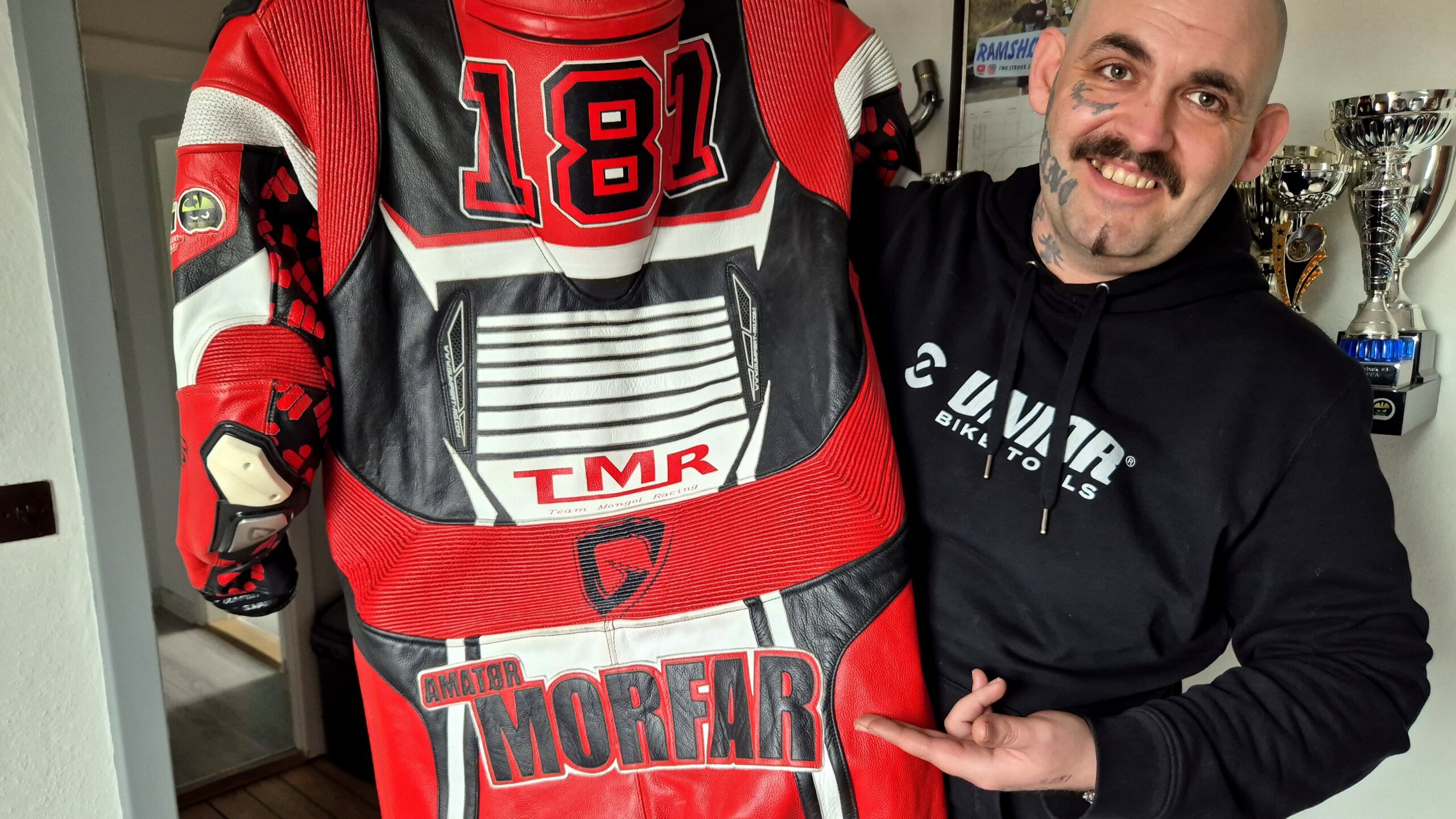 Kasper Olsen viser sin køredragt med øgenavnet “Morfar” – et navn, der har bidt sig fast i miljøet. Foto: Camilla Uth.