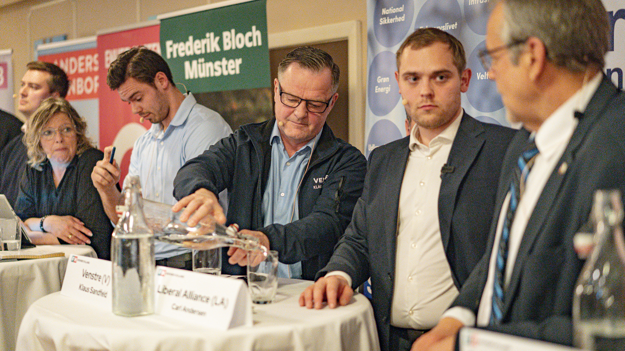 Venstre-manden Klaus Sandfeldt hælder vand op til kollegaen Carl Andersen fra Liberal Alliance. Foto: Fjodor Pedersen.