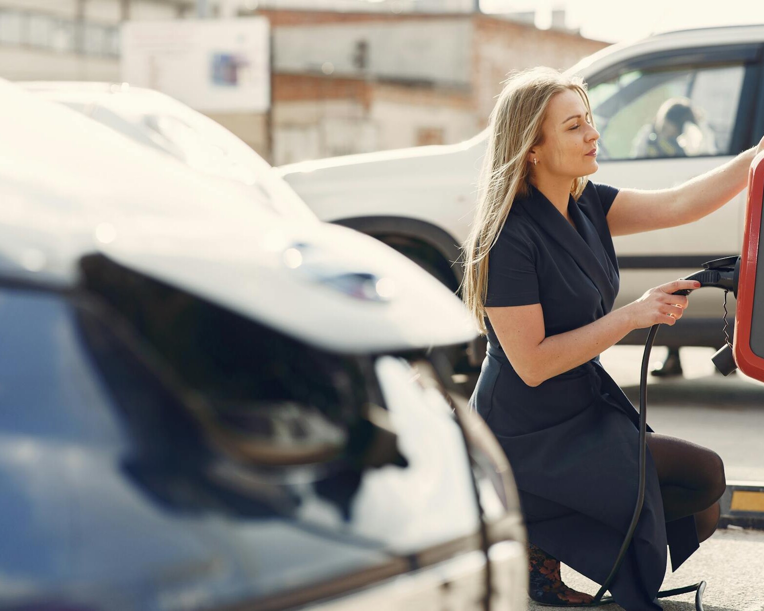 modern woman using station for charging electromobile
