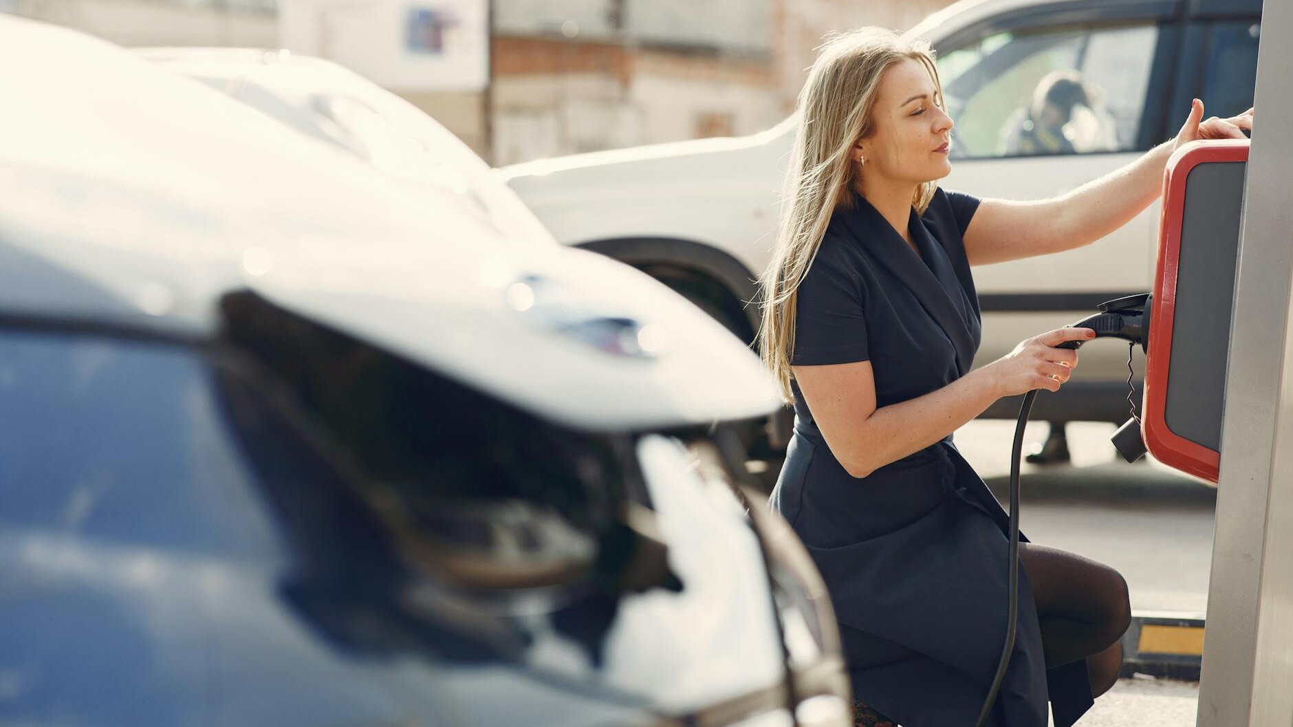 modern woman using station for charging electromobile