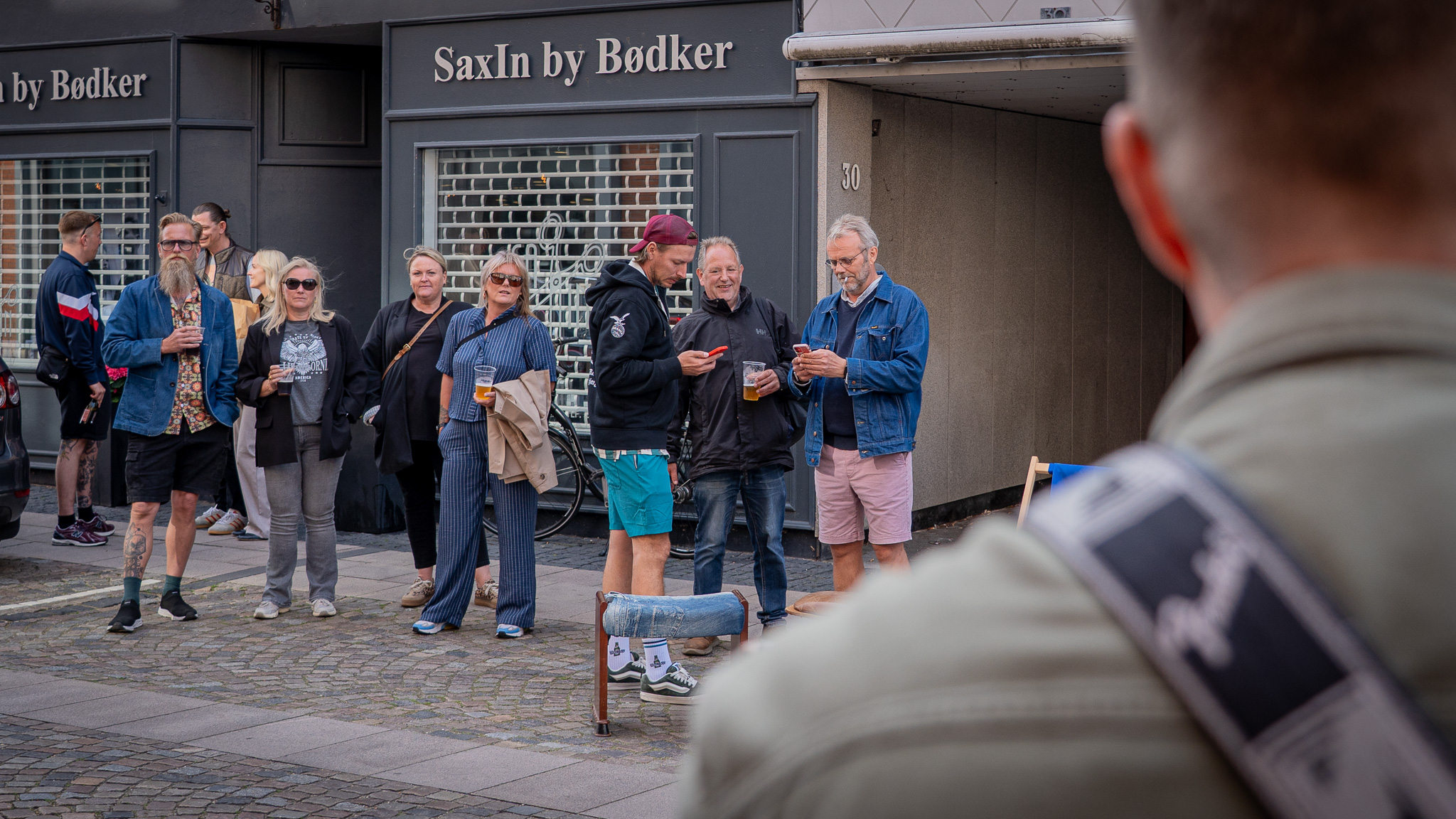 Foran herretøjsbutikken Just Ask i Torvegade gjorde mange stop for at lytte til musikken og nyde den lune sommeraften, hvor det også var muligt at få en øl serveret af Vinbarens personale. Foto: Fjodor Pedersen.