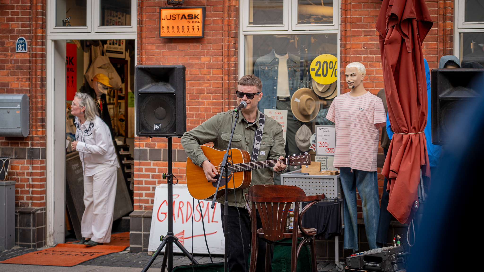 Marcus Thue Honoré optrådte foran Just Ask i Torvegade, hvor Late Night-gæsterne kunne kombinere shopping med live musik. Indehaver Ditte Lundgaard tager bestik af situationen på den orange løber. Foto: Fjodor Pedersen.