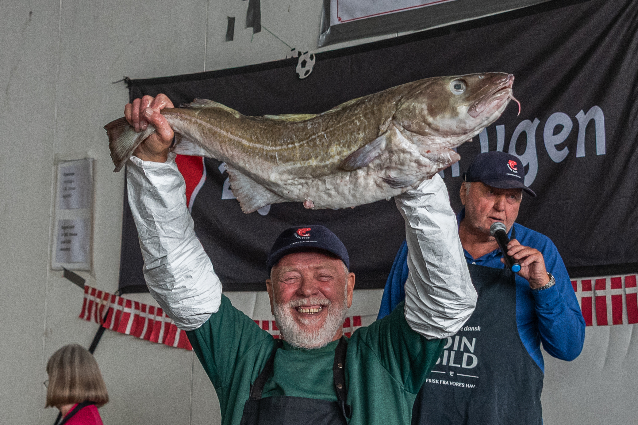 Auktionarius Geert Gregersen styrer budrunderne, mens en af de havfriske torsk fremvises for publikum under de populære fiskeauktioner på Esbjerg Havn. Foto: Claus Brinch-Danielsen.