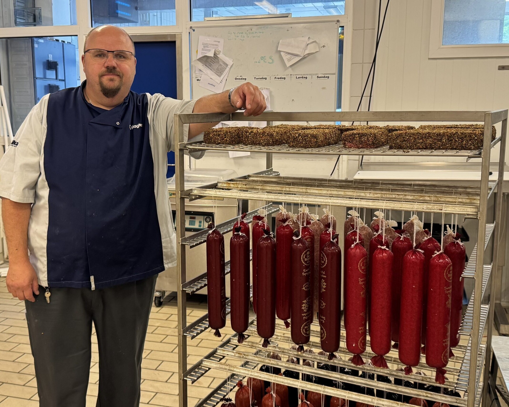 Spegepølserne hænger til modning, mens Mogens Fyhn holder et vågent øje med processen. For den erfarne pølsemager er kvaliteten altafgørende. Privatfoto.
